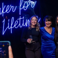 Two girls dressed in black and President Mantella stand in front of Laker for a Lifetime neon sign